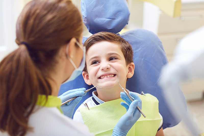 little boy sitting in dentist chair smiling at dentist