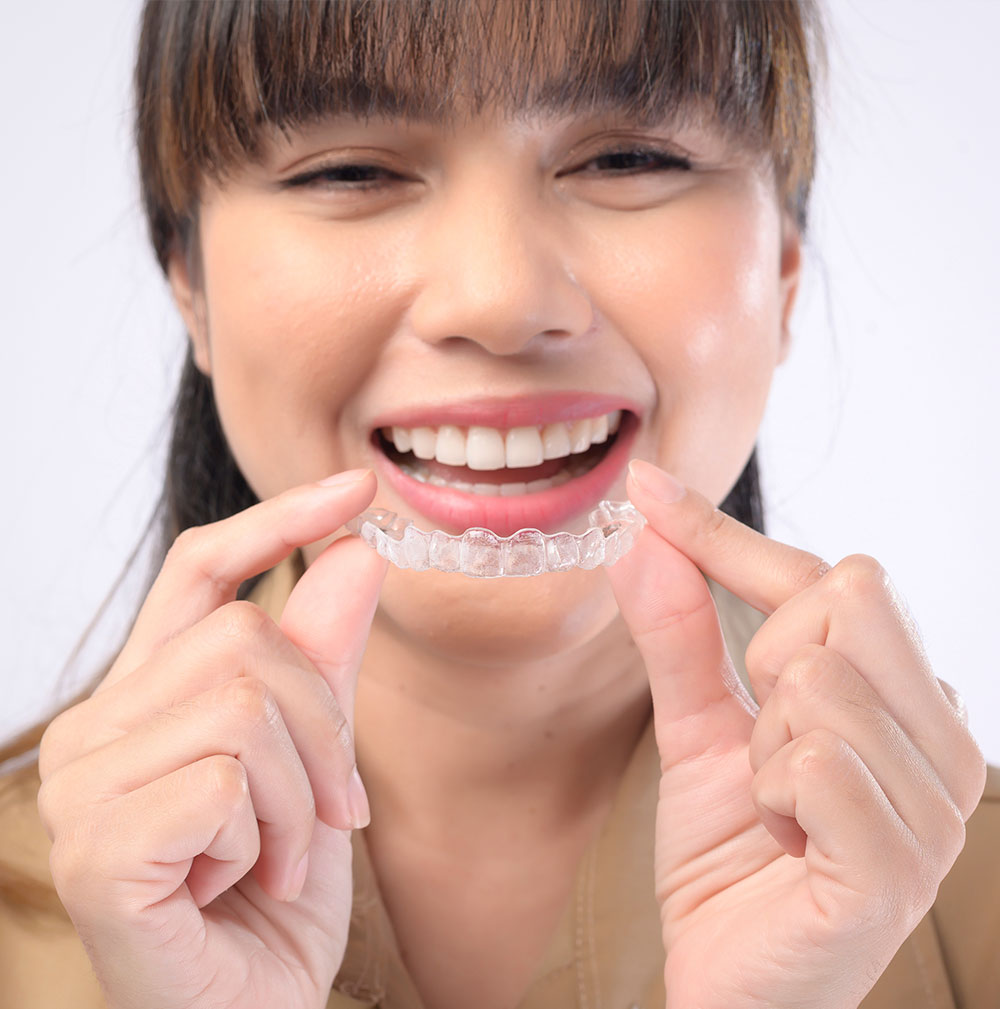 smiling young woman holding Invisalign braces